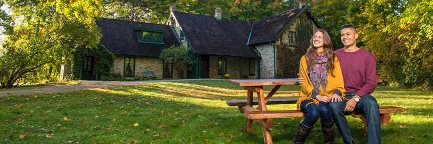 A young couple enjoying the fall colours in front of a historic Victorian era house.