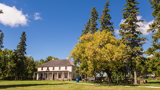 Le presbytère St. Andrew’s entouré d’arbres verts lors d’une journée d’été.