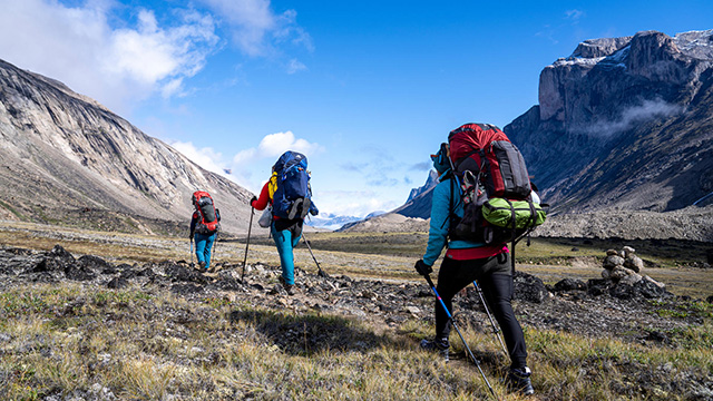 Three hikers with backpacks in Akshayuk Pass in Auyuittuq National Park.