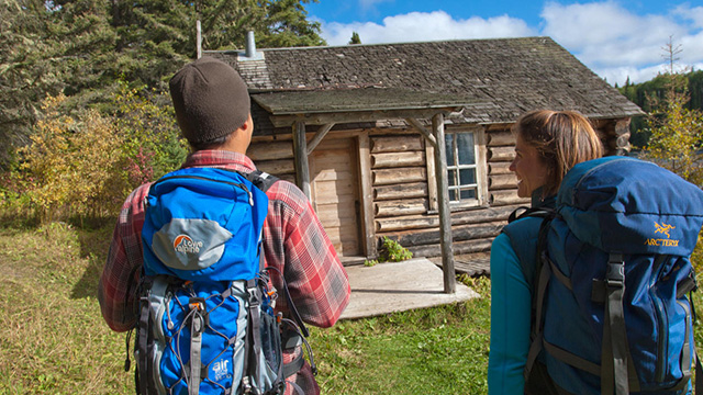 Two adults with backpacks near Grey Owl’s Cabin in Prince Albert.