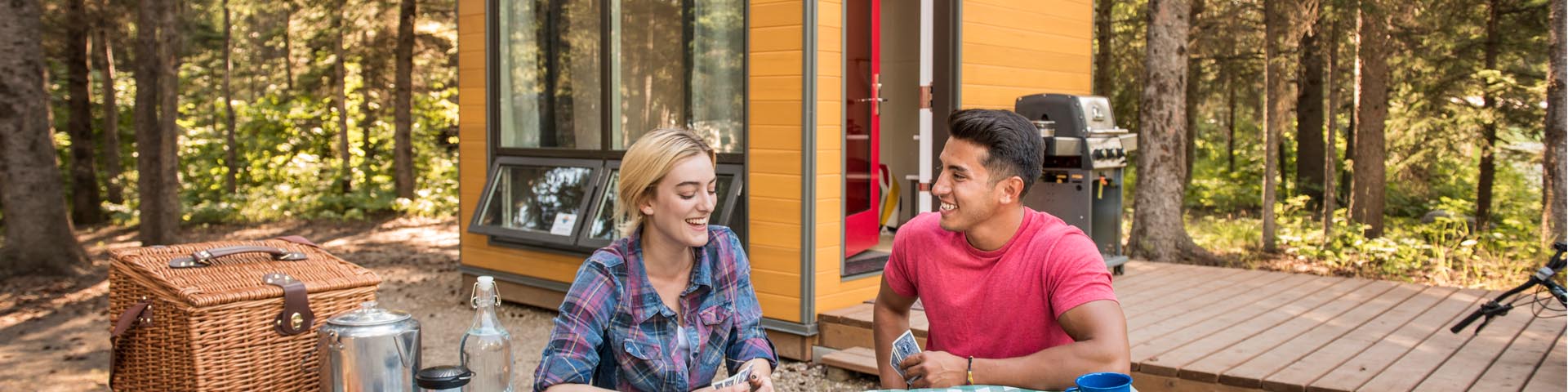  A couple play cards outside the Micro-Cube accommodations at Wasagaming Campground. 