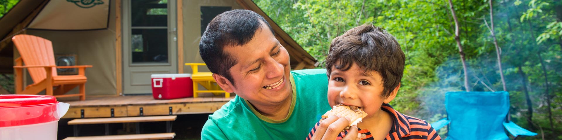 A father and son eating s’mores at an oTENTik at Cheticamp Campground