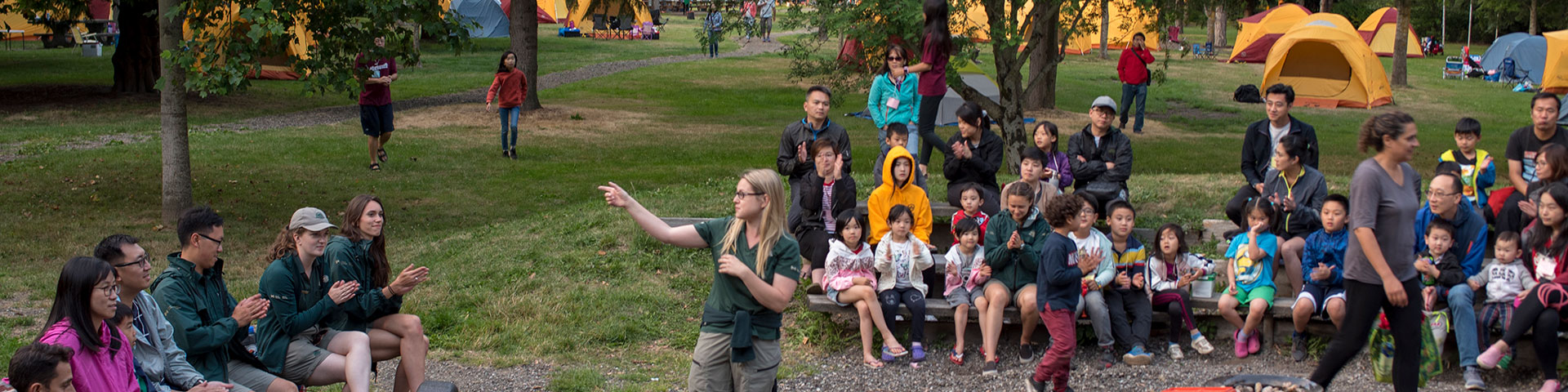 Parks Canada staff and overnight event participants sitting in a circle together with yellow tents in the background.