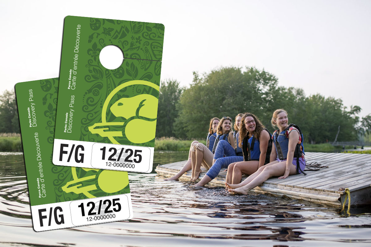 Young people sit on a dock with their feet in the water.