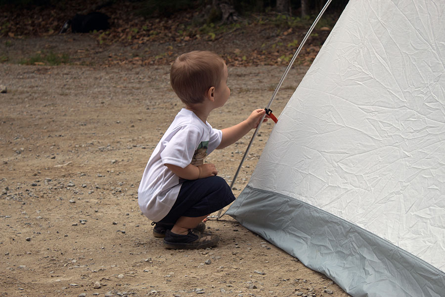 A young child clips a tent to a pole.