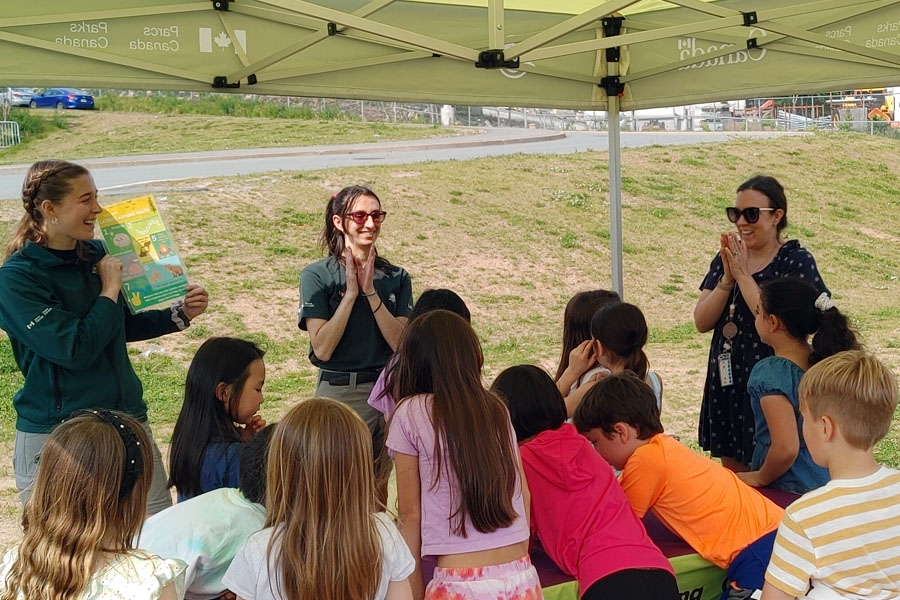 Learn-to camp staff talking to students at an outdoor booth.