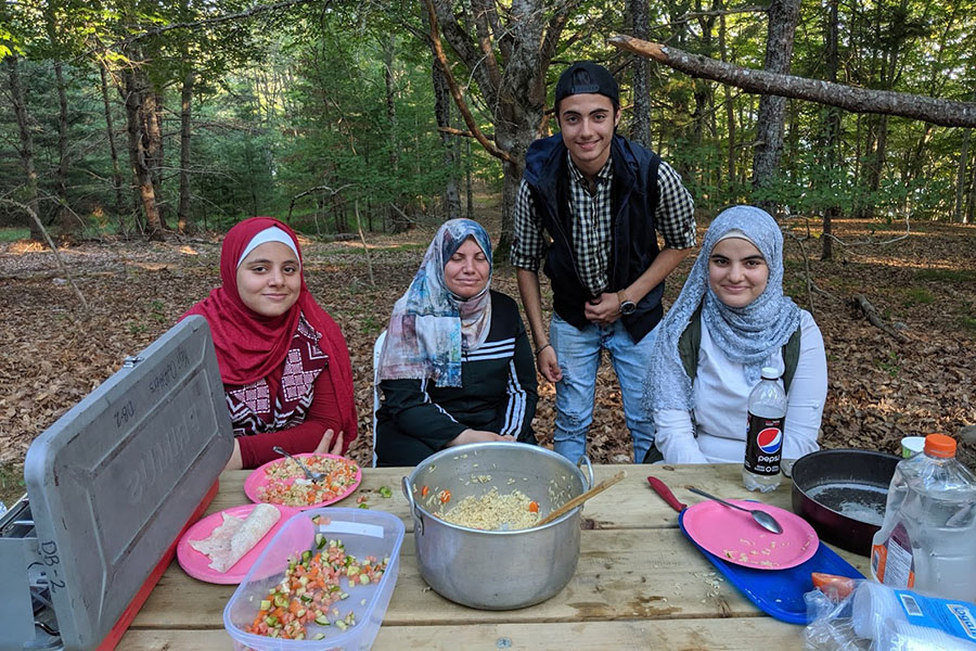Four people enjoying food cooked on a campstove.