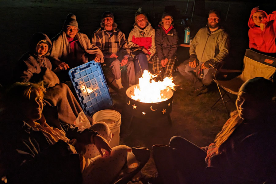 A group sits around a campfire at night.