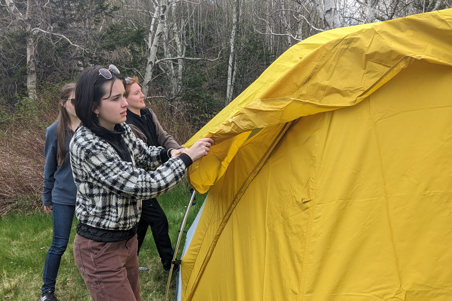 Young people work together to set up a tent.
