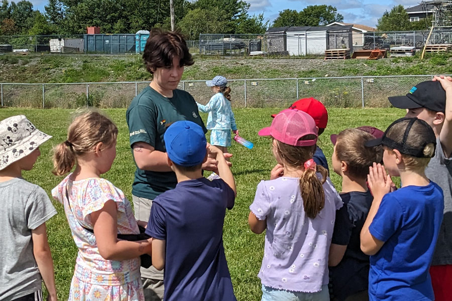 A group of children gather around a learn-to camp staff member.