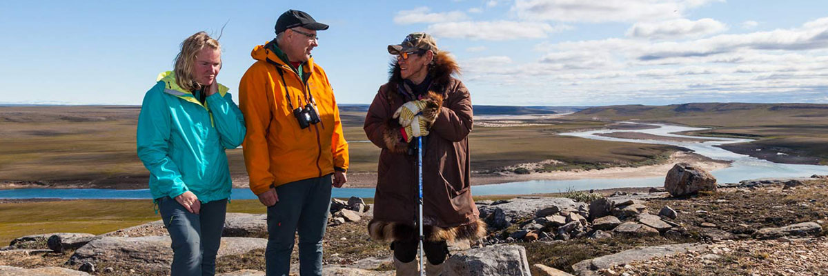 Three people on a flat rocky landscape next to a river.