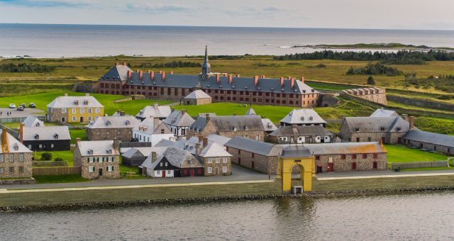 An aerial view of the reconstructed fortress between the harbour and Atlantic Ocean. The yellow frederic stands out amongst reconstructed 18th century buildings.
