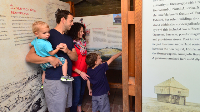 Two adults with small children read a panel in an exhibit.