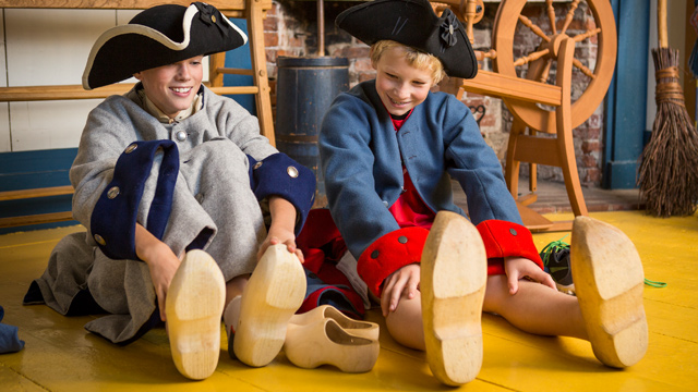Children trying on wooden shoes.