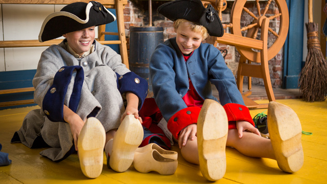 Des enfants essayent des chaussures en bois.