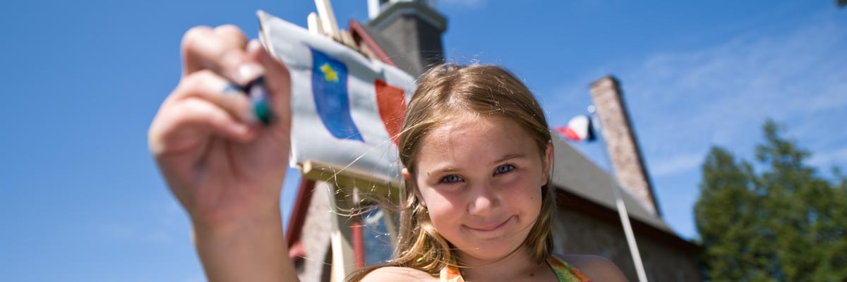 A young girl shows her drawing of an Acadian flag.