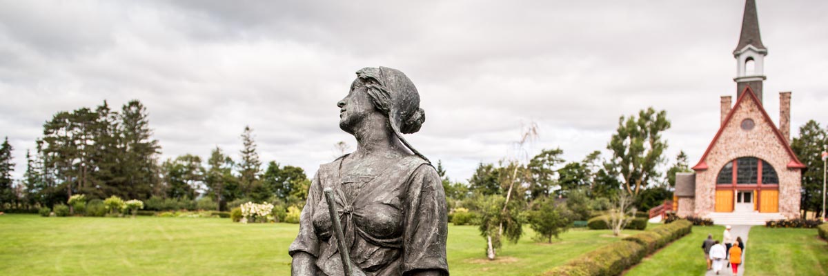 Statue d’Évangéline dans les jardins victoriens avec l’église en arrière-plan.