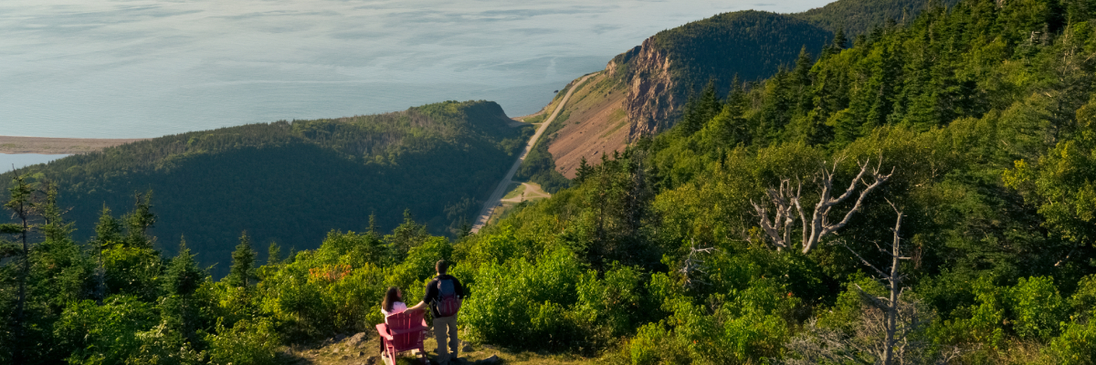 Deux visiteurs sur le sentier L’Acadien regardent l’océan et la Cabot Trail.