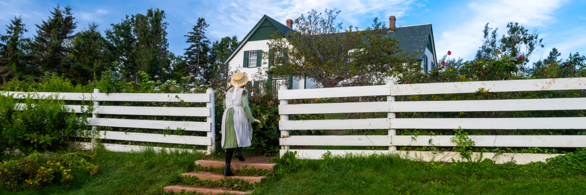Une jeune fille costumée personnifie Anne et marche vers la maison au site patrimonial Green Gables.