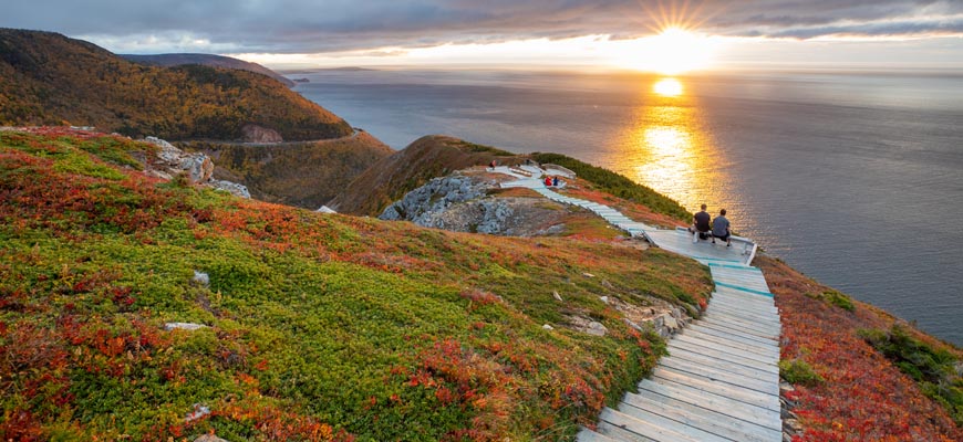 Des visiteurs sur les belvédères du sentier Skyline lors d’un coucher de soleil au parc national des Hautes-Terres-du-Cap-Breton.