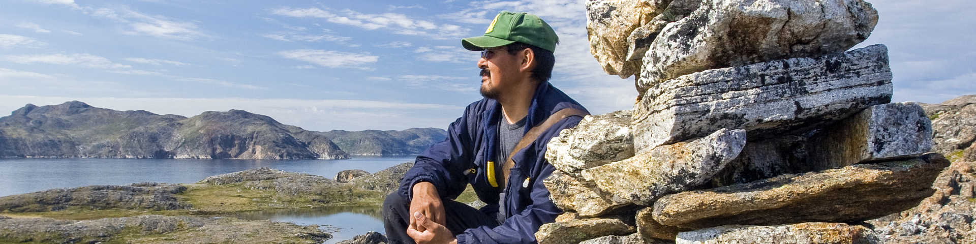 Un Autochtone sur les roches au bord de l'eau au parc national des Monts-Torngat.