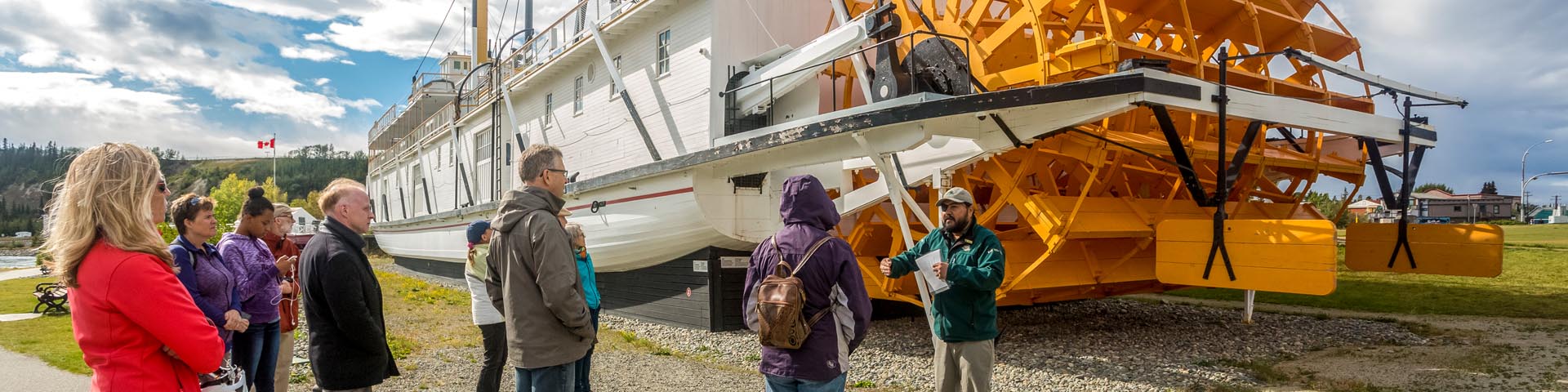 Un guide de Parcs Canada avec des visiteurs à côté du bateau au lieu historique national S.S. Klondike.