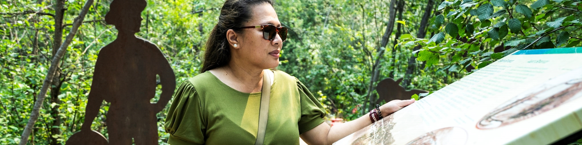 A woman is looking at an interpretive panel at the Discovery Claim National Historic Site.