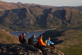 Four adults admiring the landscape, the Torngat Mountains Base Camp and Research Station and mountains in the background.