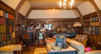 A family looking at a book in an office filled with books, and a couple couches, in the historic Laurier House.