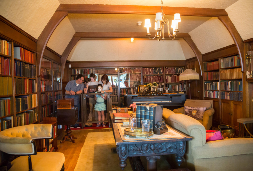 A family looking at a book in an office filled with books, and a couple couches, in the historic Laurier House.