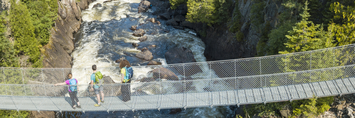 Des visiteurs admirent la vue à partir du pont suspendu de la rivière White, près des chutes Chigamiwinigum.
