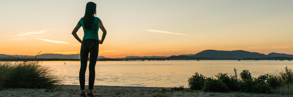 Une femme sur une plage de sable au coucher du soleil à la flèche Sidney