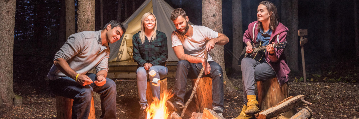 Des amis profitent de bons moments autour d'un feu de camp à proximité des tentes de trappeurs