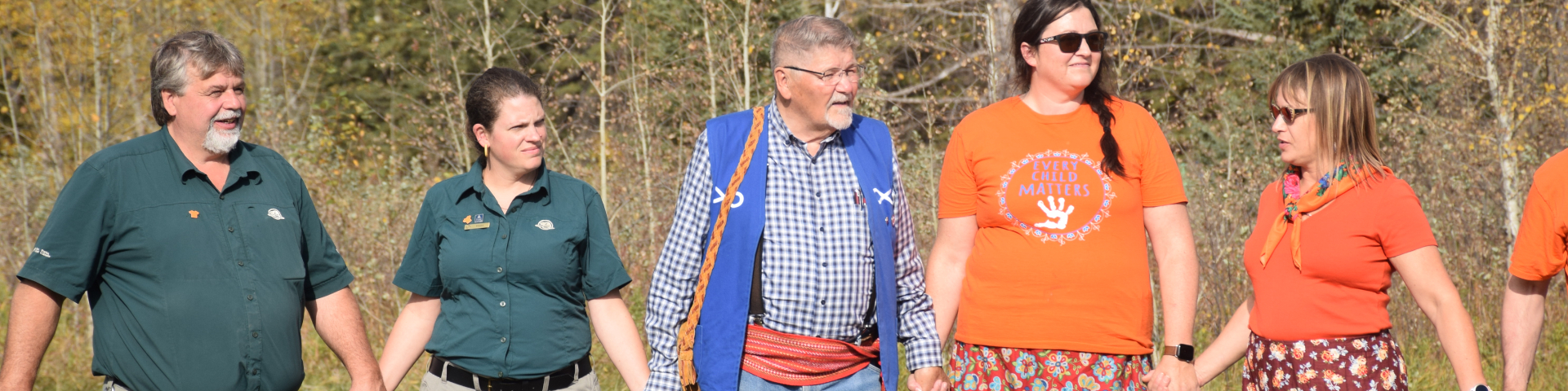Métis and Parks Canada staff members holding hands at Rocky Mountain House National Historic Site.