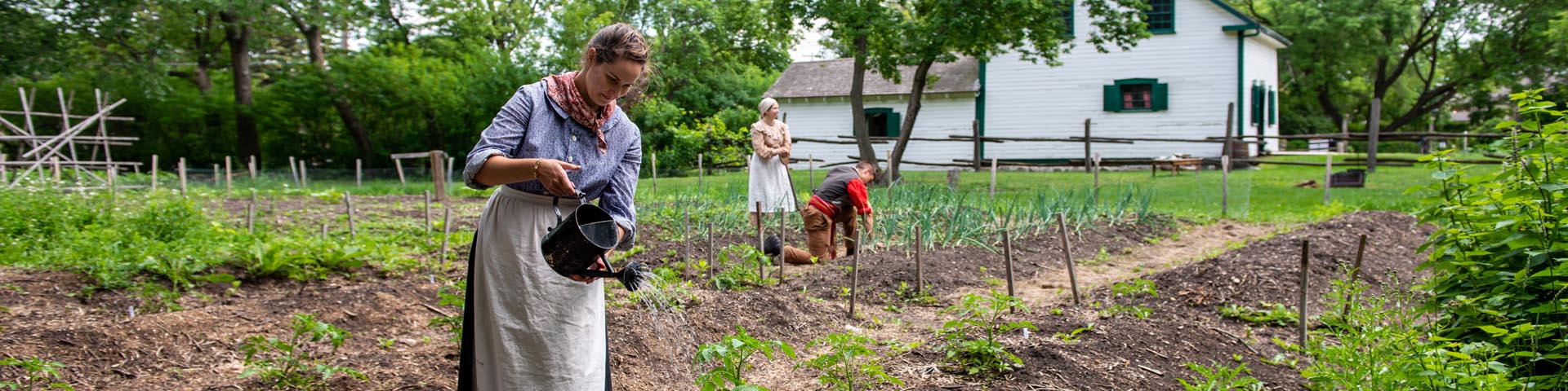 Historical interpreters tend to the Riel House garden.