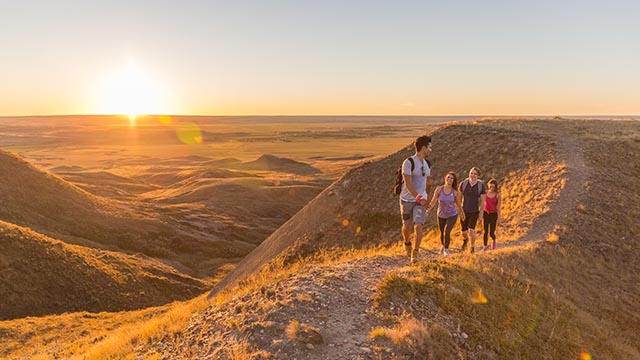 Quatre jeunes adultes en randonnée sur le sentier de Butte-70-Mile du bloc Ouest dans le parc national des Prairies.