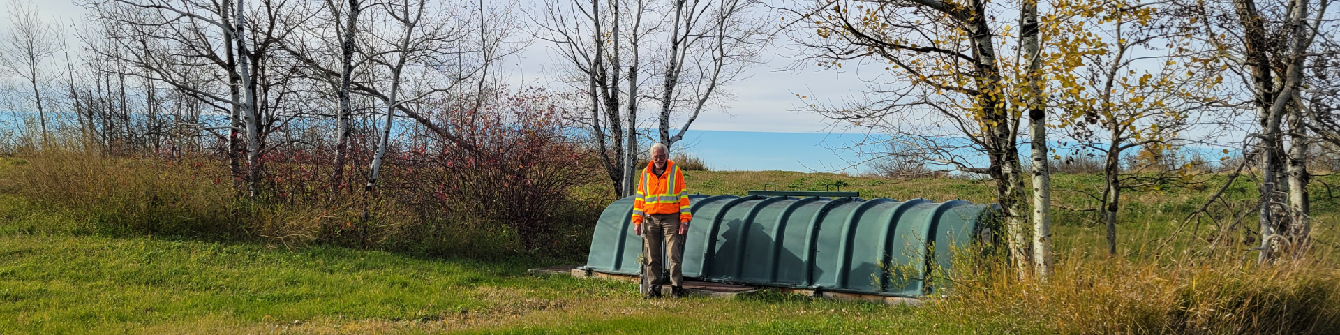 Un membre du personnel de Parcs Canada devant l'unité rotative de compostage bactérien du lieu historique national de Batoche.