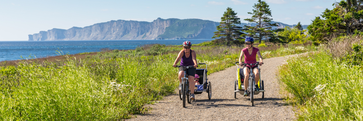 Deux cyclistes avec des remorques pour enfants sur le sentier du Banc.