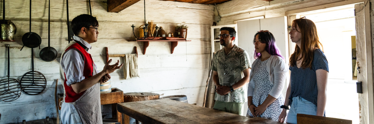 Des visiteurs avec un guide en costume d'époque au lieu historique national du FortGeorge.